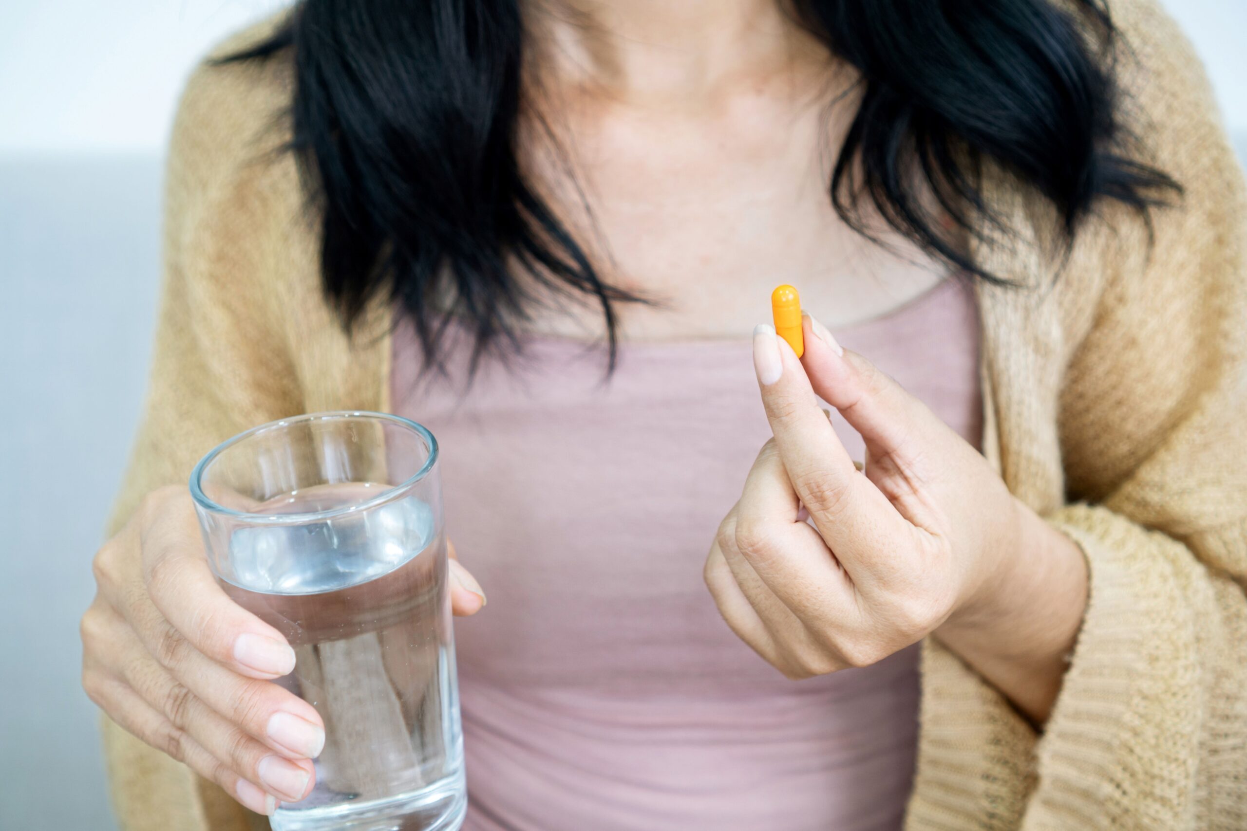 Frau nimmt Curcuma Kapsel mit einem Glas Wasser